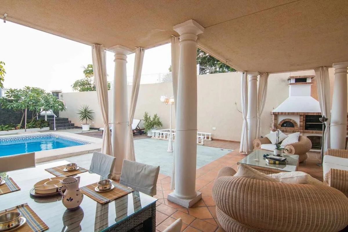 Porche con comedor exterior y barbacoa junto a la piscina